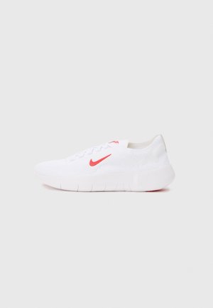 Hvide atletiksko med en tekstureret strikoverdel, rødt Nike swoosh-logo, snørebåndsdesign og hvid gummisål med grip-linjer.