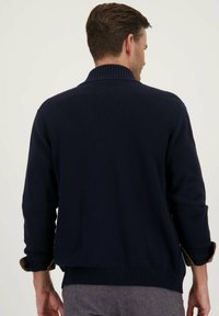 Marineblauwe trui met een geribbelde kraag en manchetten, met een gladde textuur en een aansluitend ontwerp, dat een eenvoudige en klassieke stijl toont.