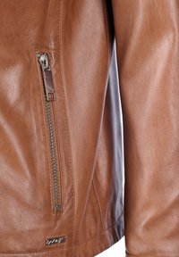 Braune Lederjacke mit einem Reißverschlussdetail am linken Ärmel, glatter Textur und einem kleinen silbernen Logo am Saum.