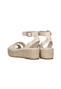 Sandalias de plataforma beige con suela de yute trenzada, correa en el tobillo ajustable y diseño de punta abierta con tiras entrecruzadas.