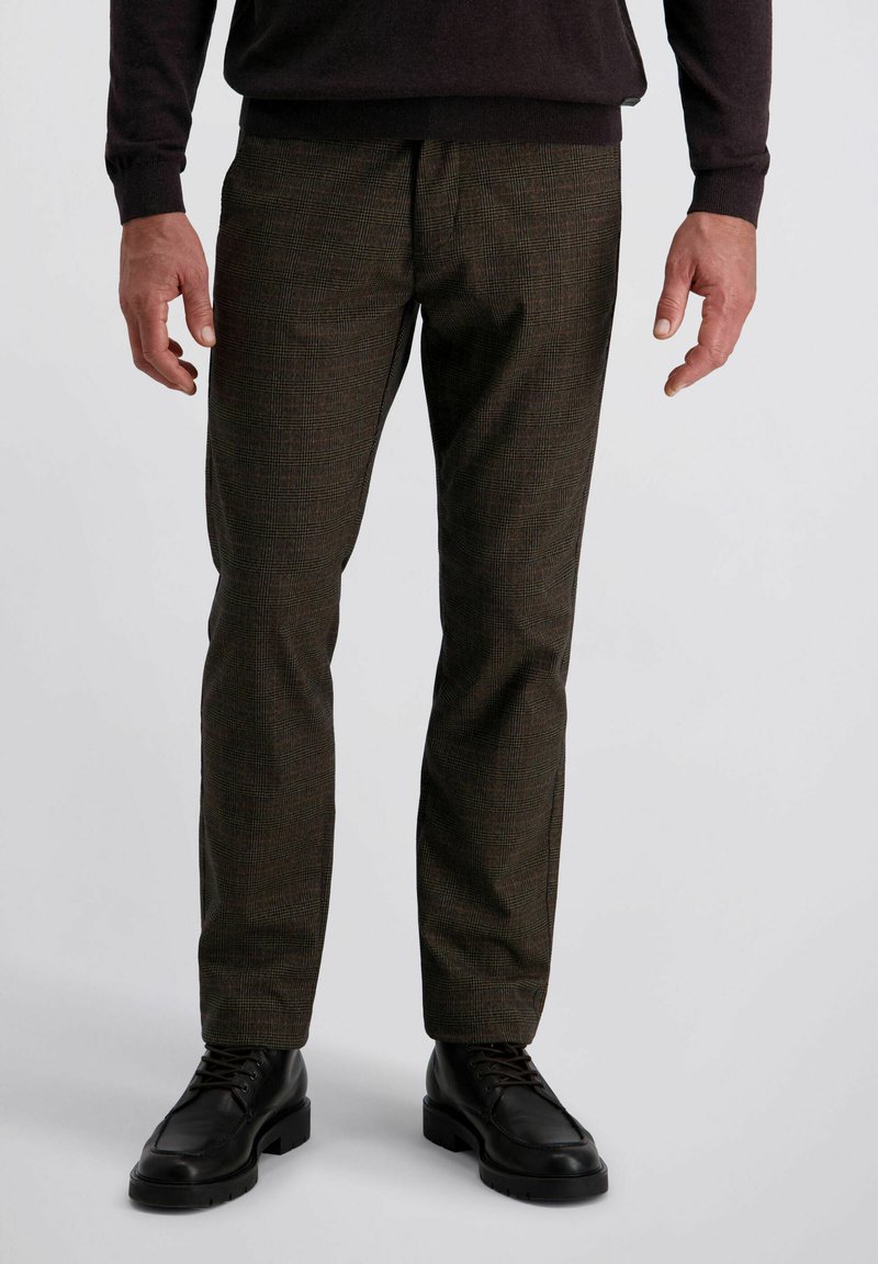 Braune karierte Hose aus strukturiertem Stoff mit schmaler Passform, kombiniert mit schwarzen Schnürschuhen mit dicker Sohle. Flacher Frontschnitt.