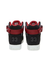 Zwarte hoge sneakers met rode accenten, voorzien van een band, textuur materiaal en witte zolen. Modelnummer "33" weergegeven op de hakken.