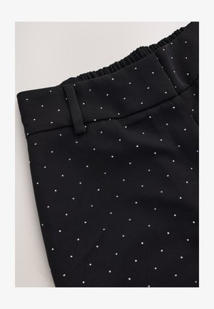 Black pants with a smooth texture, featuring a patterned design of small, silver dots. Elastic waistband and tailored structure evident.