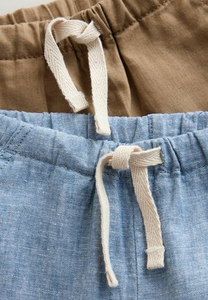 Dwie pary szortów w tkaninach beżowych i jasnoniebieskich. Mają elastyczne talii z białymi sznureczkami do ściągania oraz widoczne detale szwów.