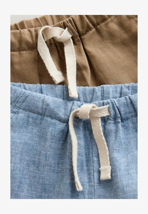 Two pairs of shorts in tan and light blue fabrics. They feature elastic waistbands with white drawstrings and visible stitching details.