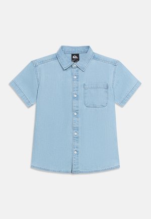 Ανοιχτό μπλε πουκάμισο από τζιν με κοντά μανίκια, κουμπιά μπροστά, τσέπη στο στήθος και κλασικό γιακά, τοποθετημένο επίπεδα σε λευκό φόντο.