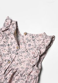 Abito floreale in tessuto rosa chiaro, con maniche arricciate, bottoni in legno e un motivo di piccoli fiori e foglie.