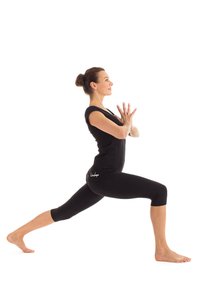 Schwarzes Sportoutfit mit einem enganliegenden Oberteil und verkürzten Leggings. Das Modell befindet sich in einer Ausfallschrittposition, barfuß, mit den Händen in einer Gebetsgeste.