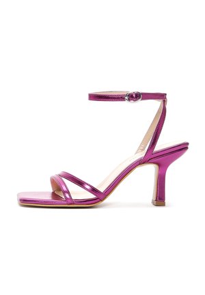 Metallic roze sandaal met hoge hak met dunne bandjes over de tenen en de enkel, voorzien van een kleine zilveren gesp en een gebogen hak van gemiddelde hoogte.