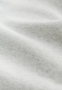 Puha, világosszürke szövet enyhén mélázott textúrával és finom hajtásokkal, amelyek finom árnyékokat hoznak létre.