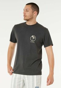 T-shirt di cotone grigio scuro con grafica circolare di una palma e testo "RIPCURL" sul lato sinistro del petto. Vestibilità standard, design con collo rotondo.