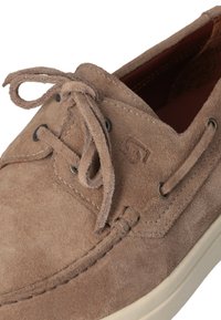 Scarpa da barca in suede marrone con punta arrotondata, suola bianca a contrasto e lacci abbinati. Presenta occhielli in metallo e dettagli di cucitura.