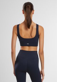 Mørkeblå ribbestrikket sportbh med brede stropper og dyp rygg, kombinert med matchende høy midje tights med sømløst design.