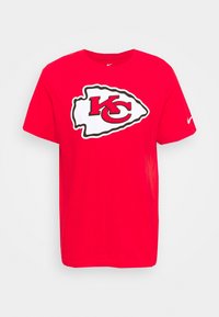 Camiseta de algodón roja con un destacado logo "KC" en blanco y negro en el frente, de manga corta y diseño de cuello redondo estándar.