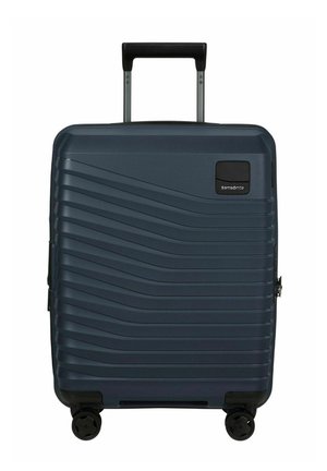 Valise rigide bleu foncé avec des rainures diagonales, quatre roues noires, poignée noire extensible et logo Samsonite en haut à droite.