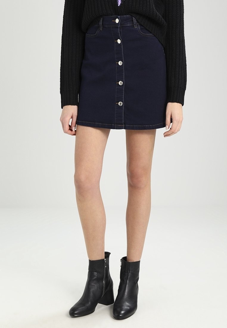 Jupe en denim foncé à silhouette ajustée, avec une fermeture à boutons sur le devant, des coutures contrastantes et une longueur mi-cuisse.