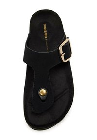 Sandale noire en suède avec une large bride, un détail en boucle en or et une accent en clou doré rond sur la semelle.