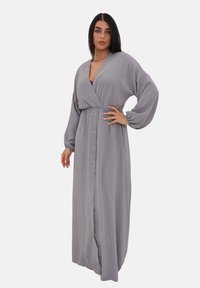 Robe grise longue avec un design enroulé, décolleté en V, manches longues et boutons sur le devant. Fabriquée à partir d'un tissu doux et fluide.