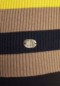 Jersey de punto acanalado con rayas horizontales en amarillo, marrón y azul marino, con una etiqueta metálica con el logo "RL" sobre un fondo liso.