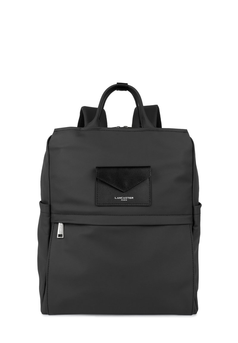 Sac à dos noir en nylon avec une texture lisse, de forme rectangulaire, poche zippée à l'avant et un petit accent en cuir noir. Deux bretelles réglables.