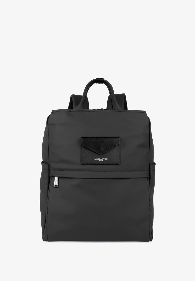 Sac à dos noir en nylon avec une texture lisse, de forme rectangulaire, poche zippée à l'avant et un petit accent en cuir noir. Deux bretelles réglables.