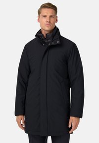 Abrigo acolchado negro con un alto cuello, con cierres a presión, bolsillos laterales y una textura mate suave. Diseño ajustado.