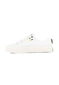 Vita canvas-sneakers med en texturerad sula, rund tåhuvud och svarta detaljer; har vita snören och en liten logotyp bak.