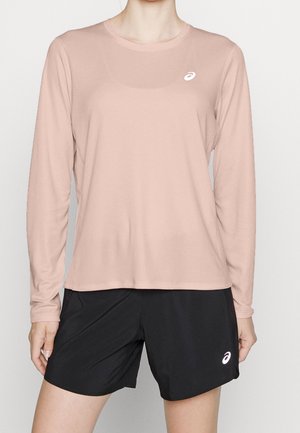 Person trägt ein hellrosa langärmeliges Sportshirt und schwarze Laufshorts, beide mit ASICS-Logos.