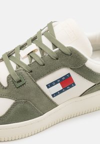 Roheline samet ja valge kangas pealisjalanõu roheliste paeltega, millel on sinine, valge ja punane "TOMMY JEANS" logo külgedel. Kummist põhi.
