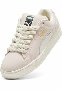 Tenisky Puma z semišu v svetloružovej farbe s hrubou bielou gumovou podrážkou. Majú jemnú tkaninu, prehnané šnúrky a zlaté logo.