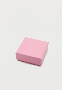 Μικρό κλειστό τετράγωνο κουτί κοσμημάτων σε υφή ροζ υλικού σε απλό λευκό φόντο.
