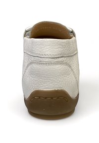 Białe skórzane buty casualowe widziane z tyłu, z brązową gumową podeszwą i widocznym szwem na teksturowanej skórzanej cholewie.