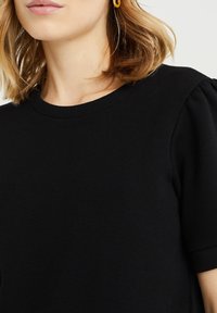 Zwarte katoenen t-shirt met korte mouwen, ronde hals en subtiele pofmouwen, met een gladde, zachte textuur.