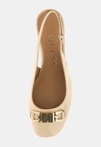 Scarpa slingback in pelle verniciata beige con punta quadrata, dettaglio in metallo dorato e cinturino alla caviglia regolabile. Suola piatta con logo interno.