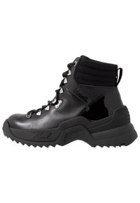 Bota de senderismo negra con acabado brillante de cuero charol, cuello de malla texturizado y suela resistente; cuenta con ojales y cordones plateados.