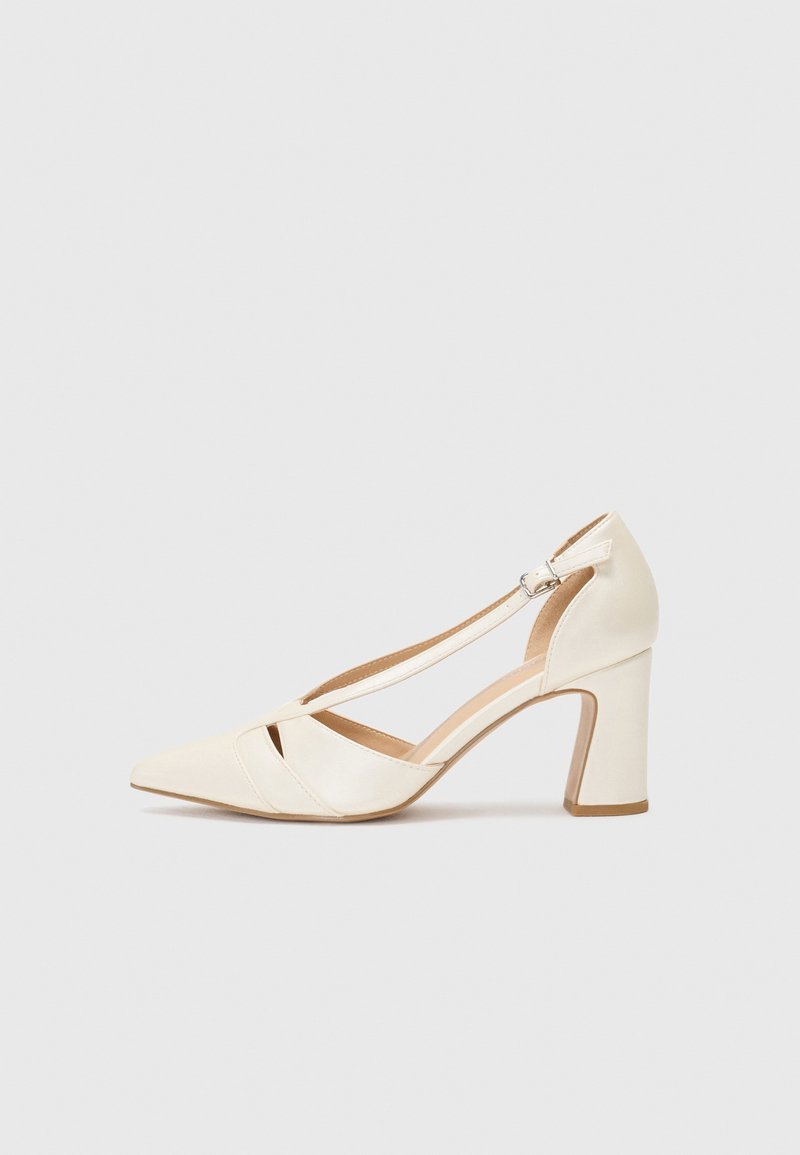 Scarpa con tacco alto in pelle bianca con punta affusolata e design a taglio. Presenta una fascia con fibbia argentata e un tacco a blocco.