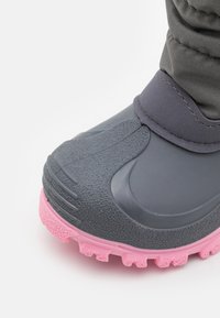 Γκρίζα αδιάβροχη μπότες με υφασμάτινη επιφάνεια, ευλύγιστη καουτσούκ σόλα και ροζ λεπτομέρειες. Διαθέτει ραμμένο μανσέτα και σχέδιο με ραβδωτή μύτη.