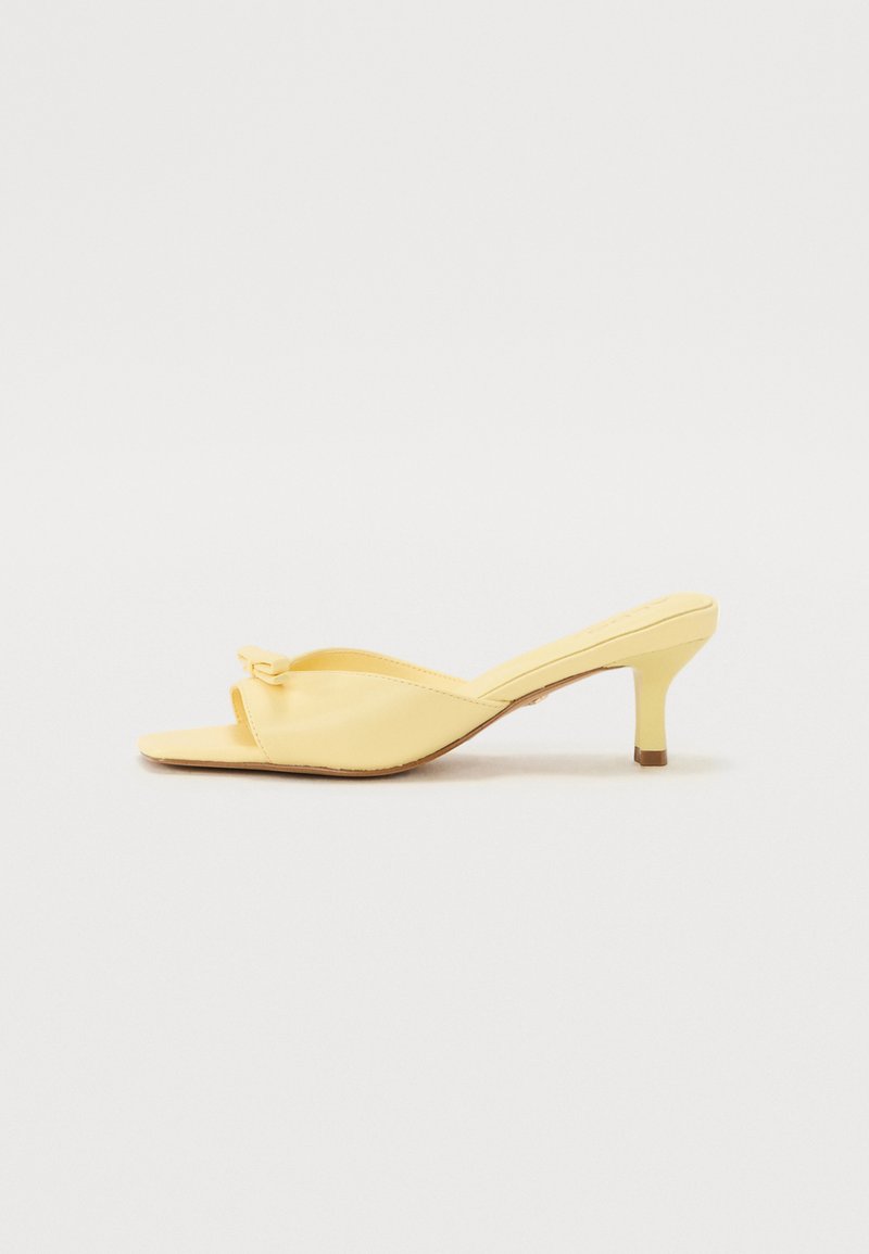 Yellow faux leather mules with a pointed toe, open heel, and a small block heel. Features a decorative bow at the front.