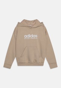 Beige hoodie i mjukt tyg, med en framficka, ribbade ärmslut och en vit "adidas SPORTSWEAR" logotyp på bröstet.