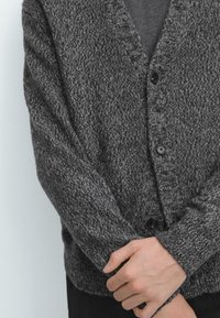 Koldgrå stickad kofta av texturerat tyg med V-ringning, knappar fram och långa ärmar.