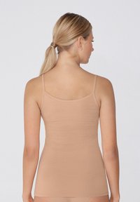 Beżowy top na ramiączkach z cienkimi paskami, dopasowany, wykonany z miękkiego materiału, charakteryzujący się gładką fakturą i prostym, niezdobionym stylem.