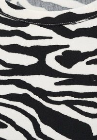 Zwart-wit zebra print stof met een zachte textuur, featuring gedurfde, golvende strepen en een ronde halslijn met contrasterende stiksels.