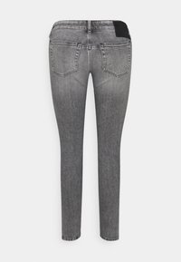 Jeans in denim grigio slim fit con una finitura sbiadita, dotati di due tasche posteriori e di una toppa nera in vita. Texture liscia su tutta la superficie.