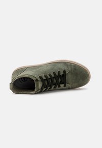 Sneaker din suede verde cu talpă din cauciuc maro, șireturi de un verde închis și un interior moale, texturat. Design subțire cu vârf rotund și accente cusute.