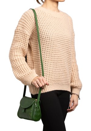 Beige gebreide trui met een getextureerd patroon en ballonsleeves, gecombineerd met een kleine groene leren schoudertas met een afgeronde flap.