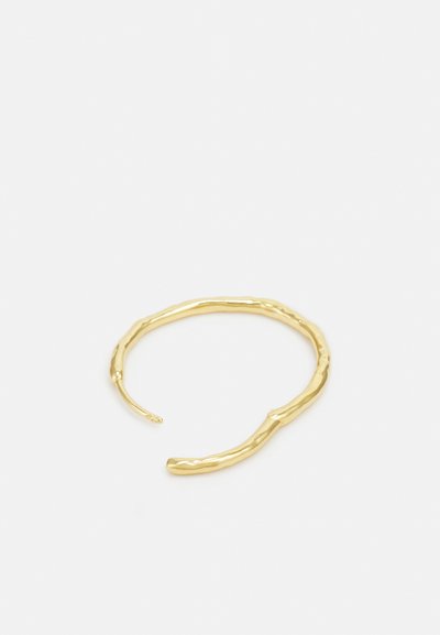 Brățară cuff din aur cu o textură ondulată și organică, având un design deschis, cu capete ușor conice pentru o ajustare confortabilă.