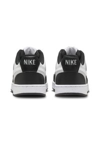 Sneakers Nike con tomaia in pelle bianca e dettagli neri, linguetta in mesh testurizzato e logo sul tallone, montati su una suola in gomma bianca.