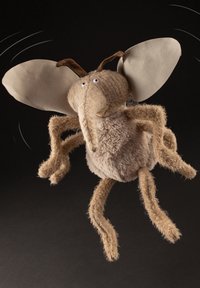 Soft plush toy resembling a flying insect with a round beige body, long fuzzy limbs, large two-toned ears, and small eyes.