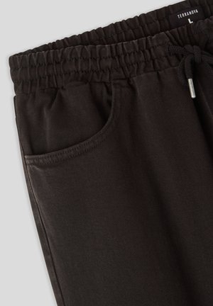 Pantaloni jogger neri con una vita elasticizzata a coste, chiusura con coulisse e una tasca laterale. Il tessuto presenta una sottile trama.