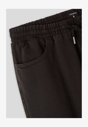 Pantaloni jogger neri con una vita elasticizzata a coste, chiusura con coulisse e una tasca laterale. Il tessuto presenta una sottile trama.